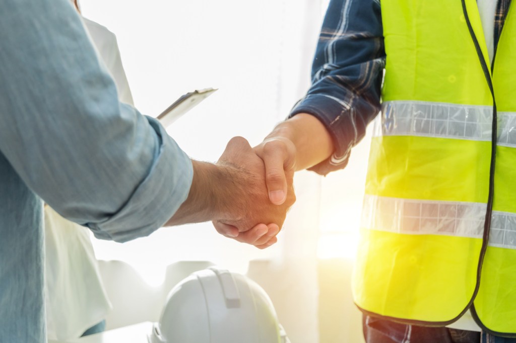 Two individuals shaking hands, one wearing a fluorescent safety vest, symbolizing partnership in industrial repair services.