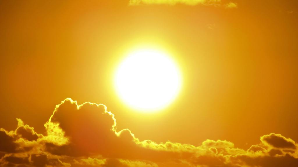 Bright sun against a golden sky with fluffy clouds.